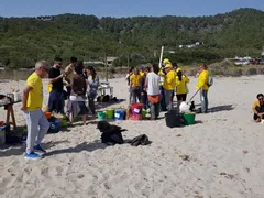 Voluntarios con chaleco amarillo de Voluntaris d'Eivissa clasificando residuos en cubos y cestas