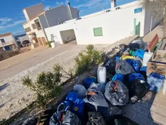 Bolsas de basura y garrafas de plástico apiladas junto a una calle de Formentera