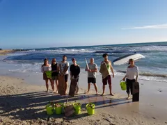Grupo de voluntarios de One Planet One Life con cubos verdes tras una limpieza de playa en 2019