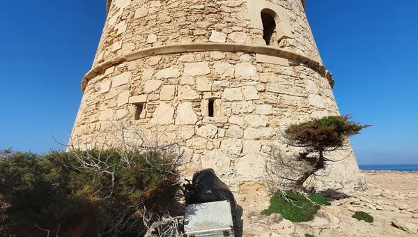 Electrodoméstico abandonado junto a una torre de defensa histórica en Formentera